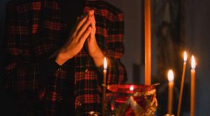 Hands in prayer in front of candles-2