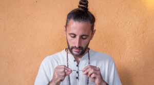 A person holding and looking at a beaded necklace, which is likely a mala