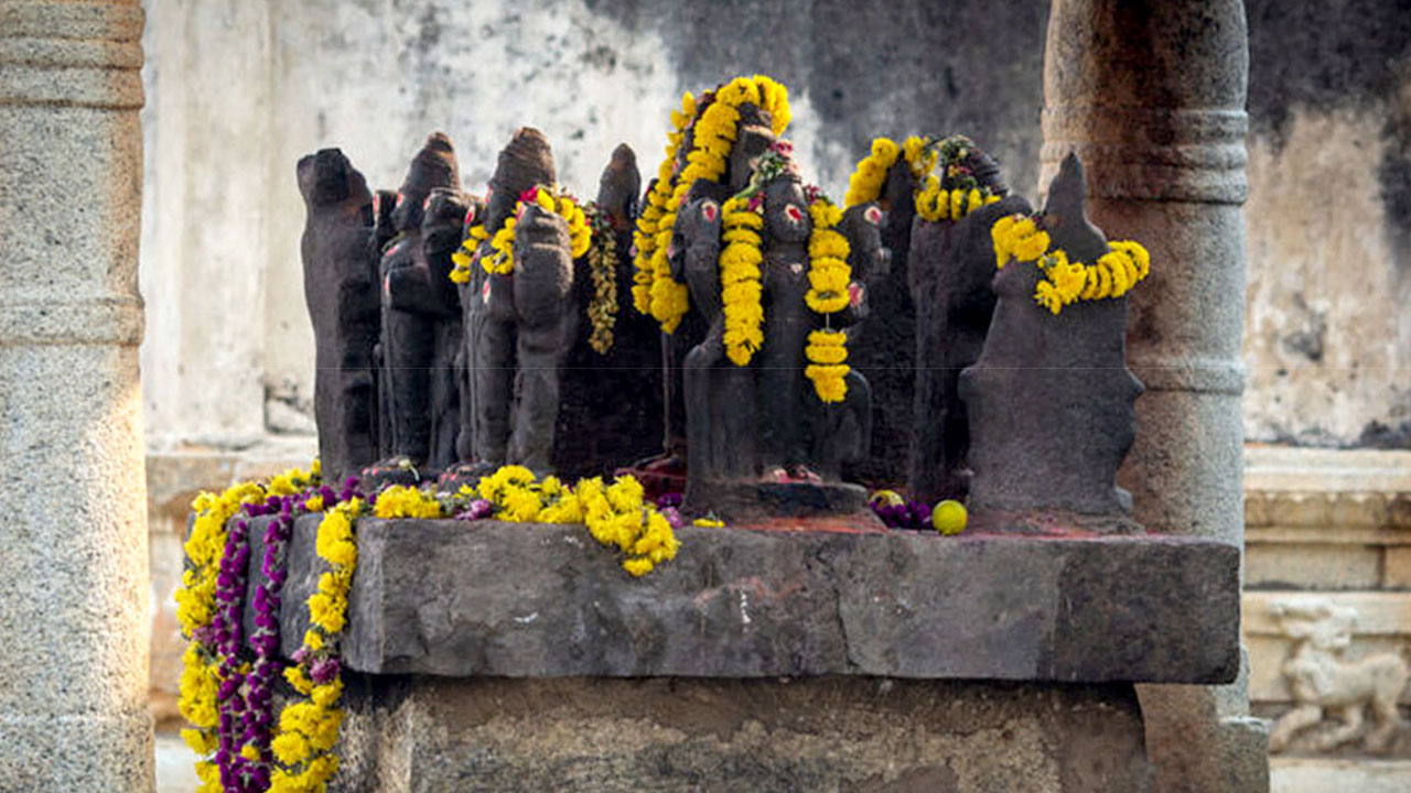 Stone shrine figures draped with marigold garlands at a temple
