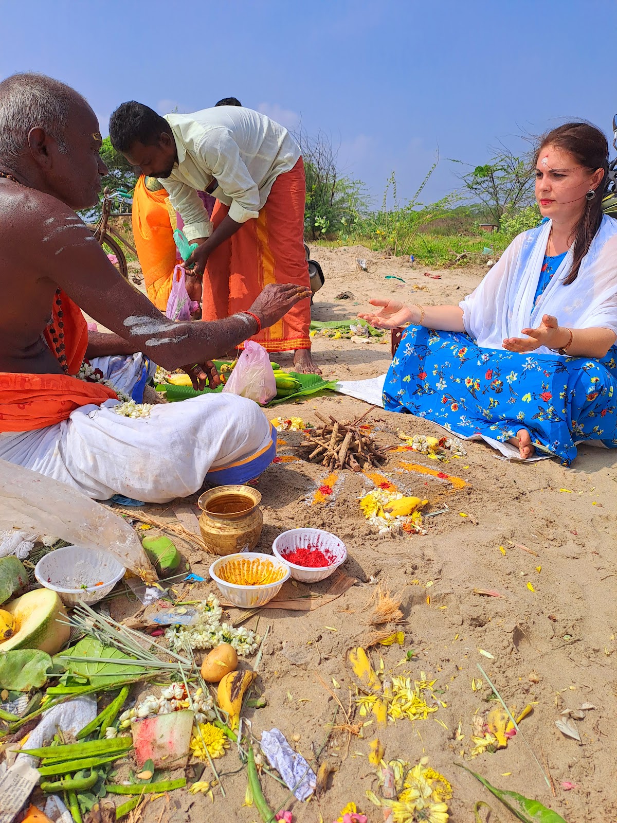 Woman in a blue sari in a riverside ritual with a priest during a South India pilgrimage