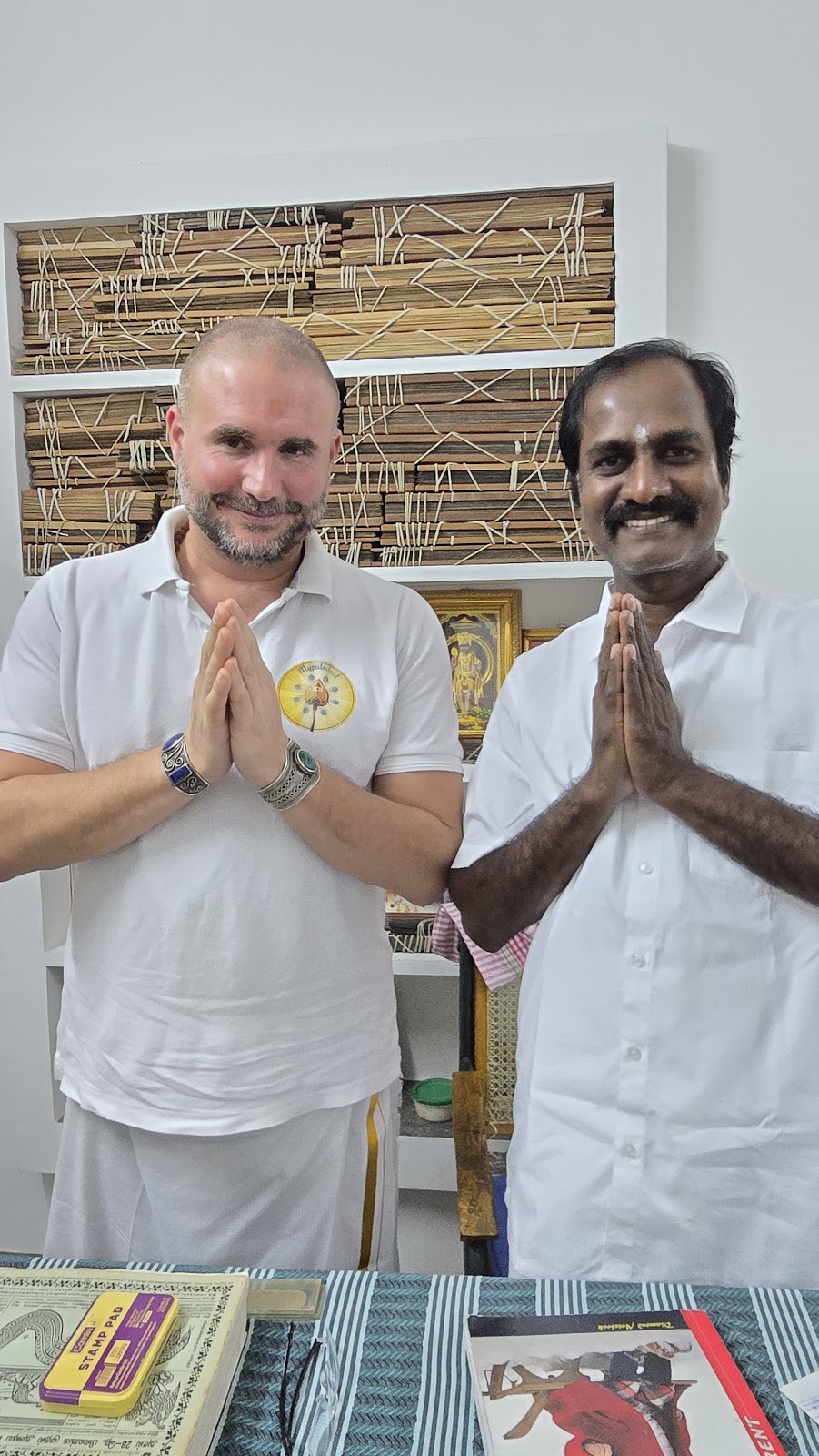 Two men greeting with namaste in a palm leaf reading room in South India
