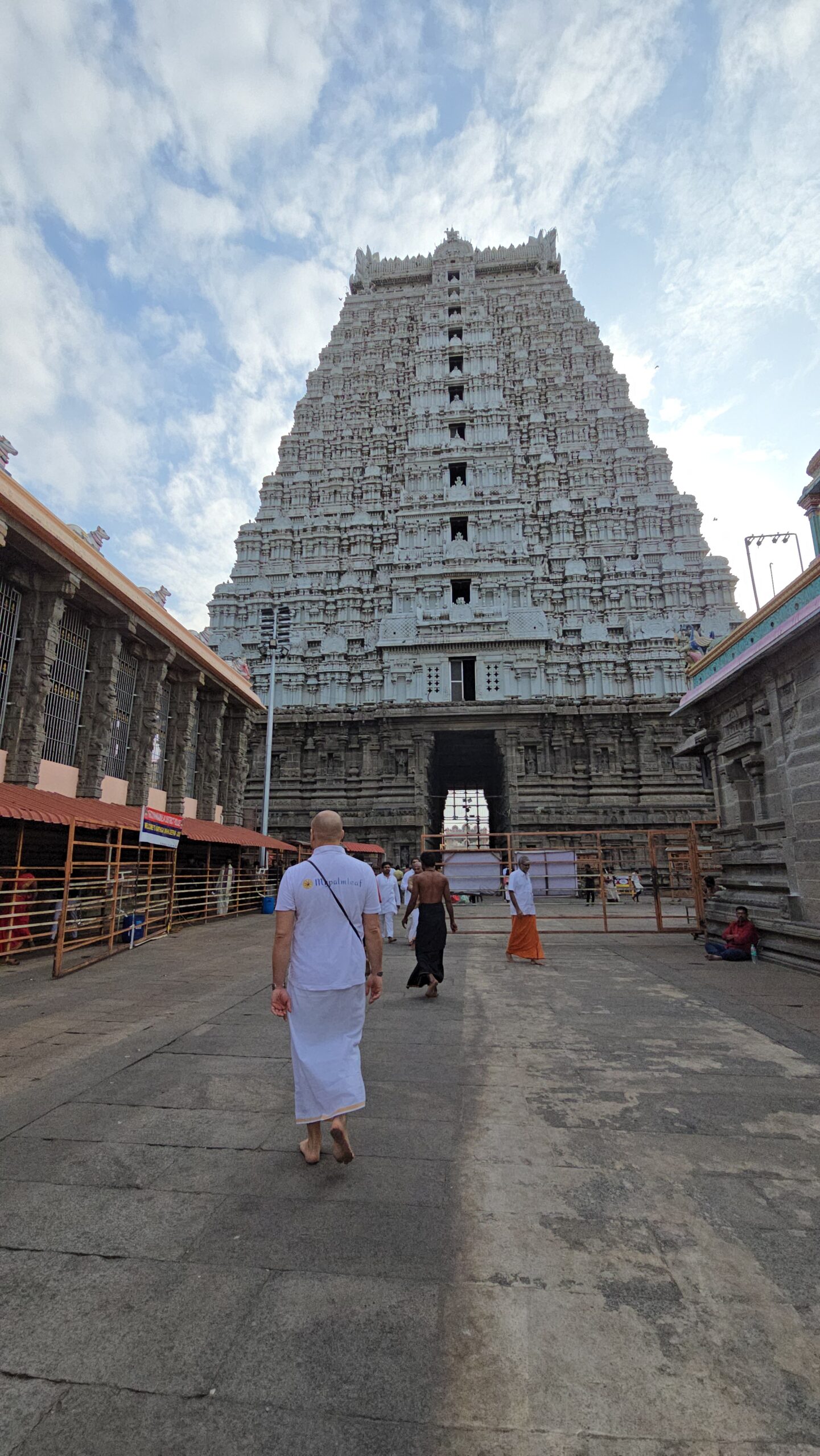 Visitor walking toward the towering white gopuram of a South Indian temple