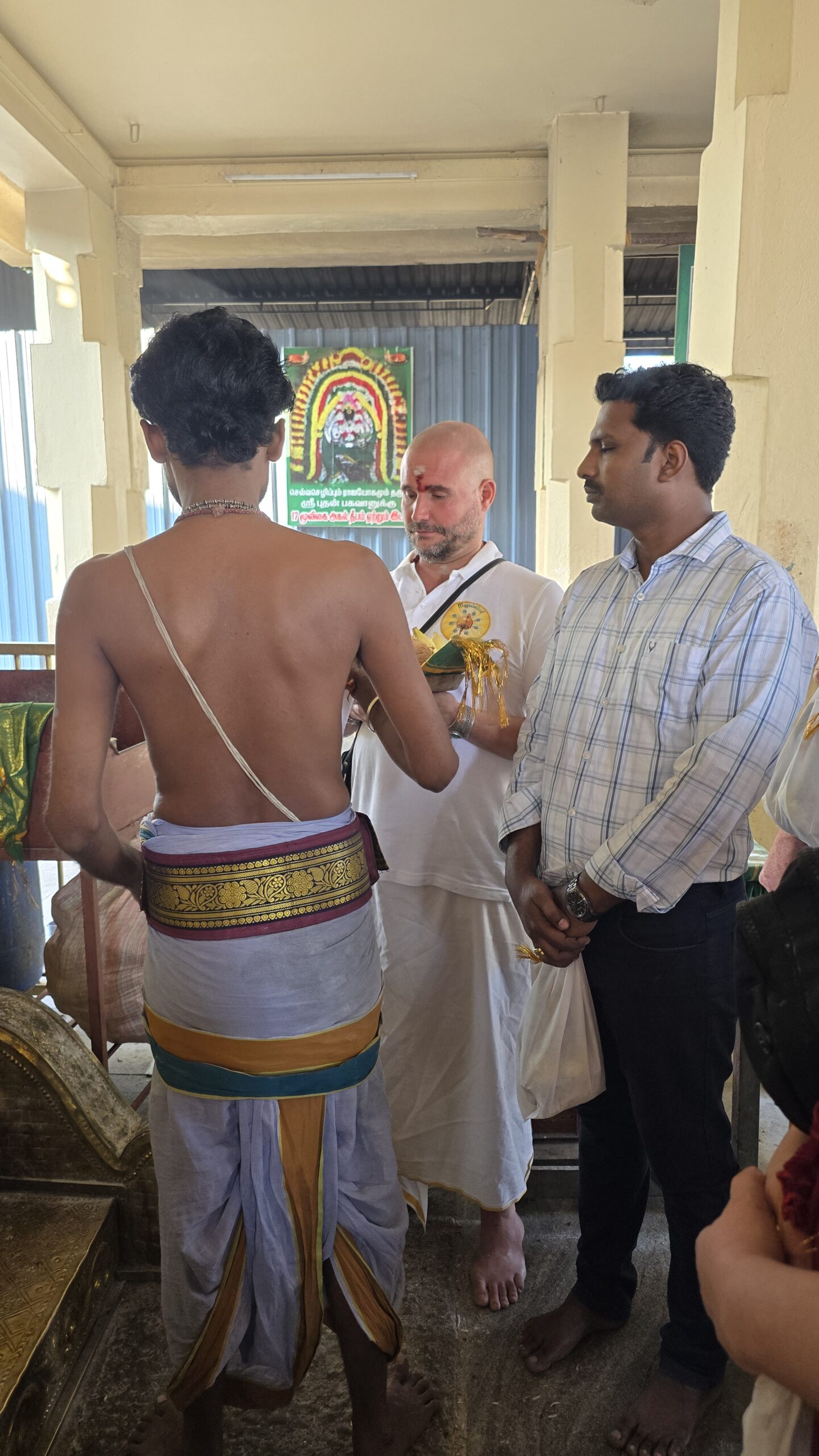 Visitor receiving a blessing from a young priest before a temple shrine