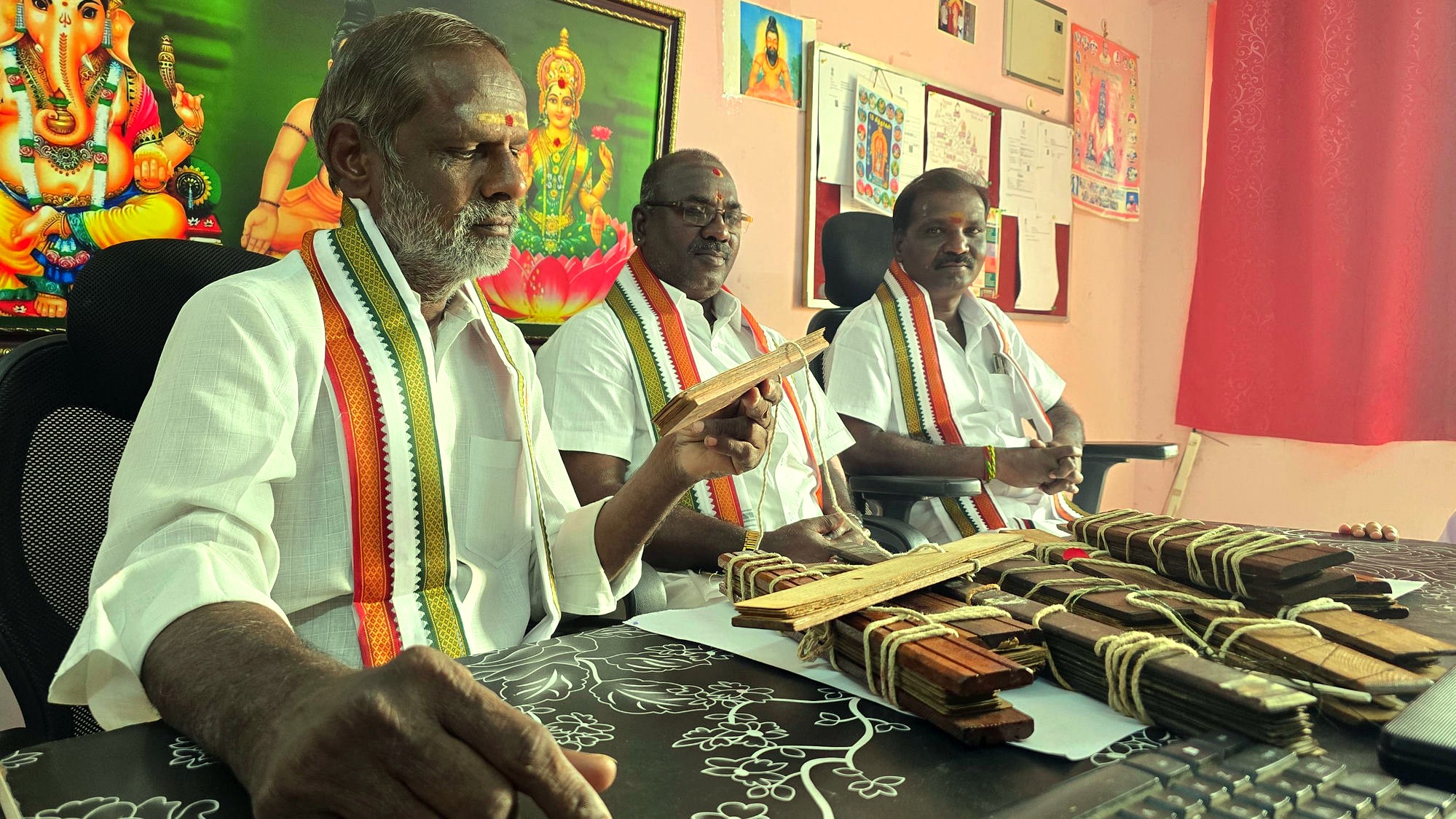 Three Nadi readers with palm leaf manuscripts at their desk