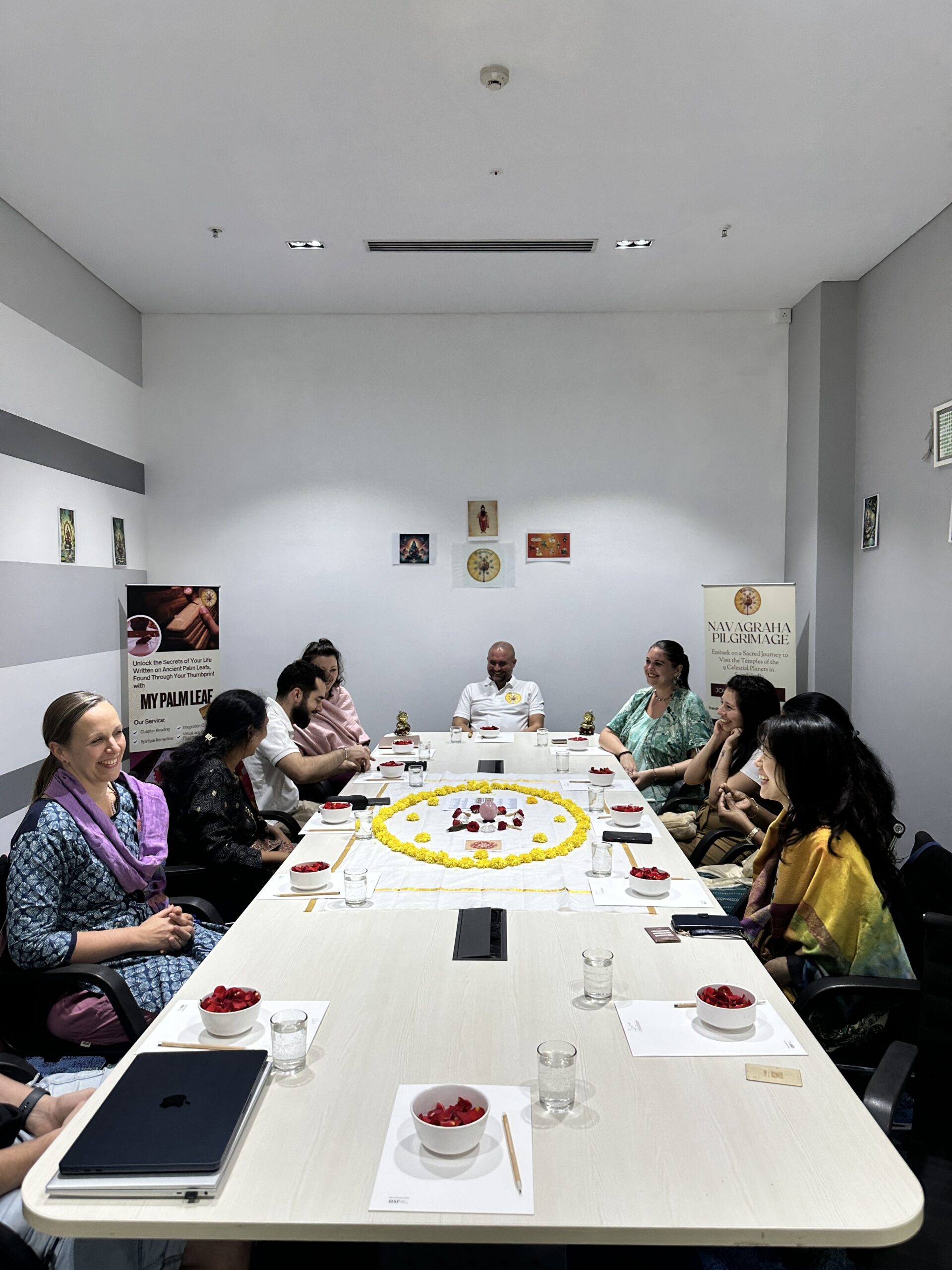 Mypalmleaf participants seated around a flower mandala at a Navagraha pilgrimage gathering