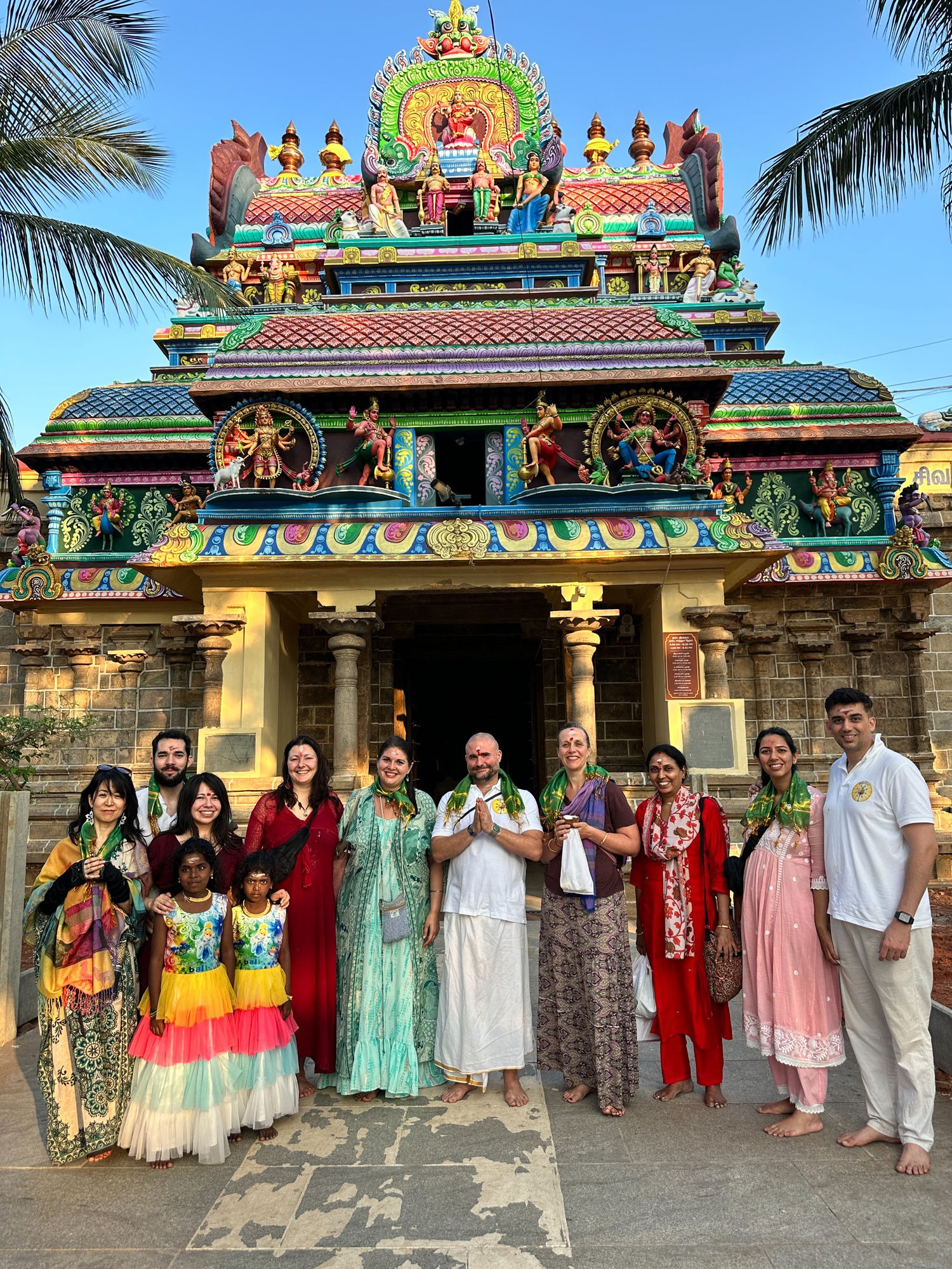 Mypalmleaf pilgrimage group with garlands at a colourful South Indian temple in the evening