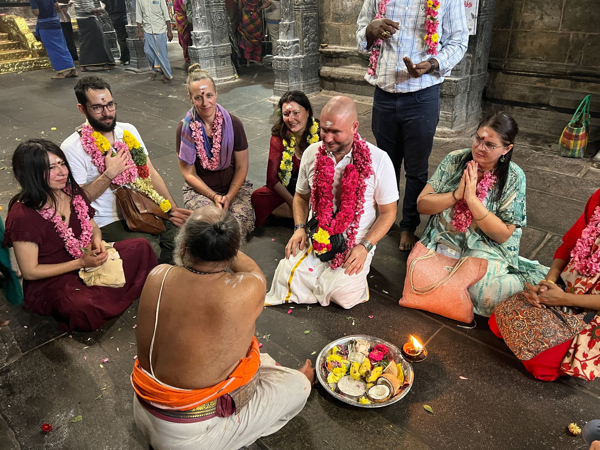 Mypalmleaf group receiving an archana ritual from a priest at a temple