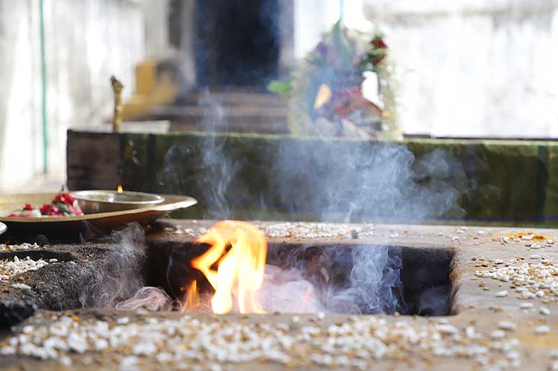 Fire offering (homa) ceremony with rice and flames in a temple