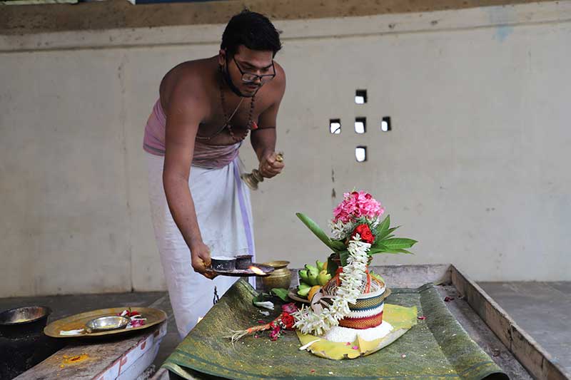 Priest performing a ritual offering over a flower-draped shrine