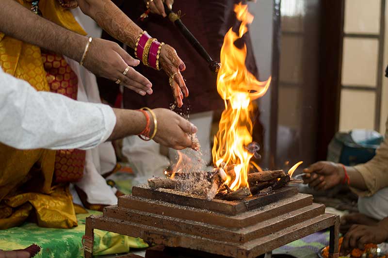 Hands offering grains into the sacred fire during a Hindu ceremony