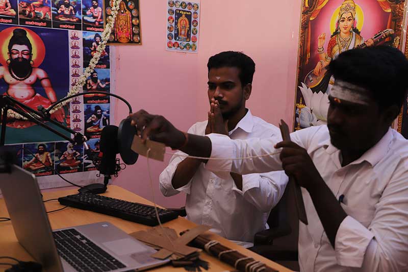 Nadi reader presenting a palm leaf strip at a microphone during a reading
