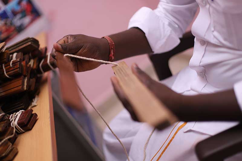 Nadi reader measuring thread over a palm leaf manuscript bundle