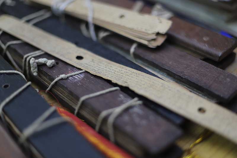 Close-up of bundled ancient palm leaf manuscripts tied with string