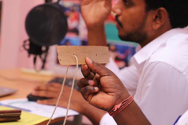 Nadi reader holding a single palm leaf strip during a recorded reading