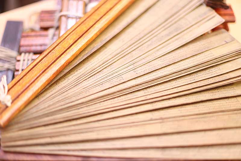 Fanned edges of a thick stack of inscribed palm leaf manuscripts