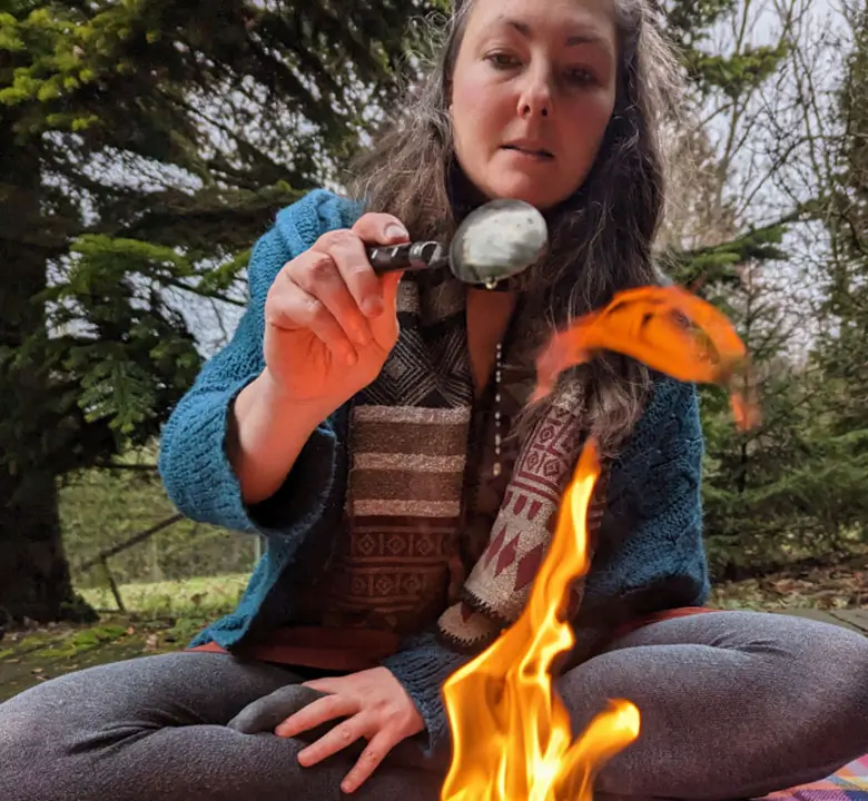 Woman performing a fire ceremony outdoors holding a ritual spoon