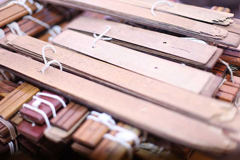 A pile of cord-bound ancient palm leaf manuscript bundles in an archive