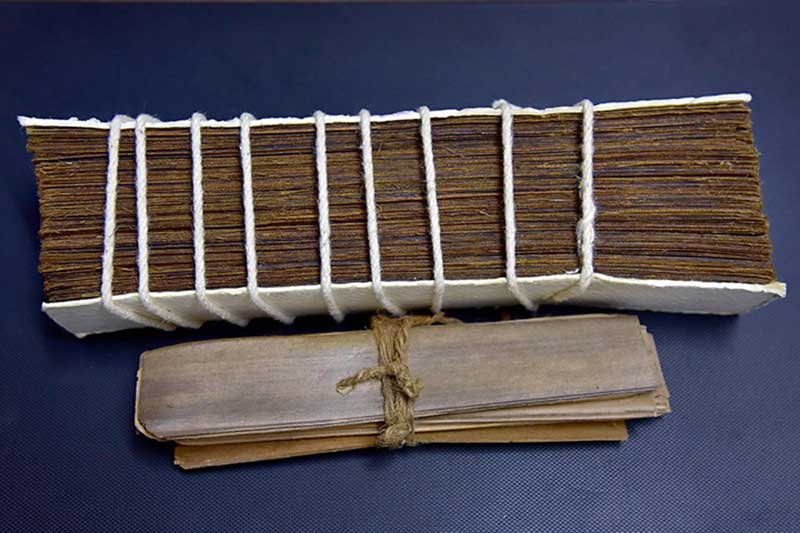 Cord-bound palm leaf manuscript bundles on a dark surface