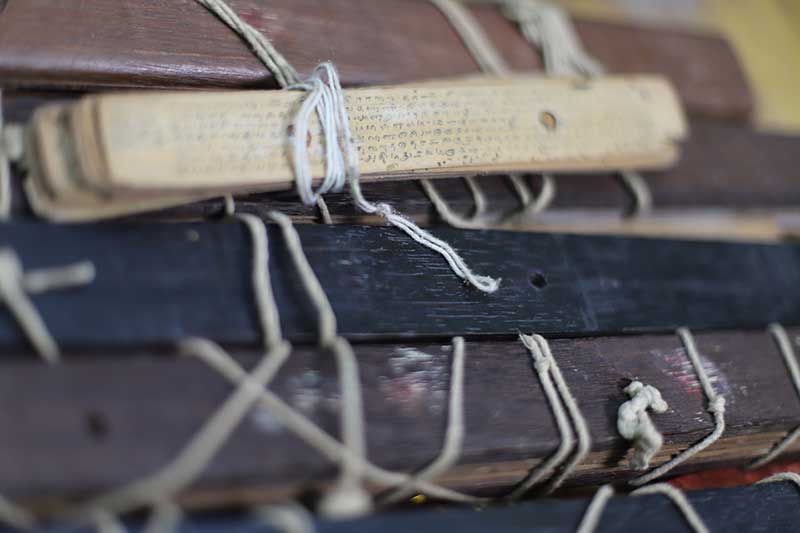 Bundle of palm leaf manuscripts tied with white cord in an archive