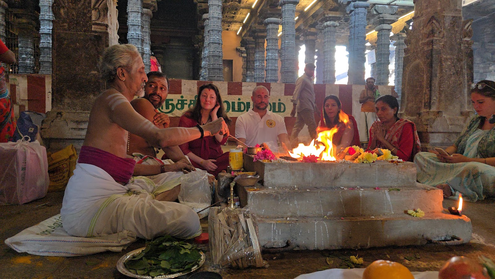 Priest performing a homa fire ceremony with a group at a temple