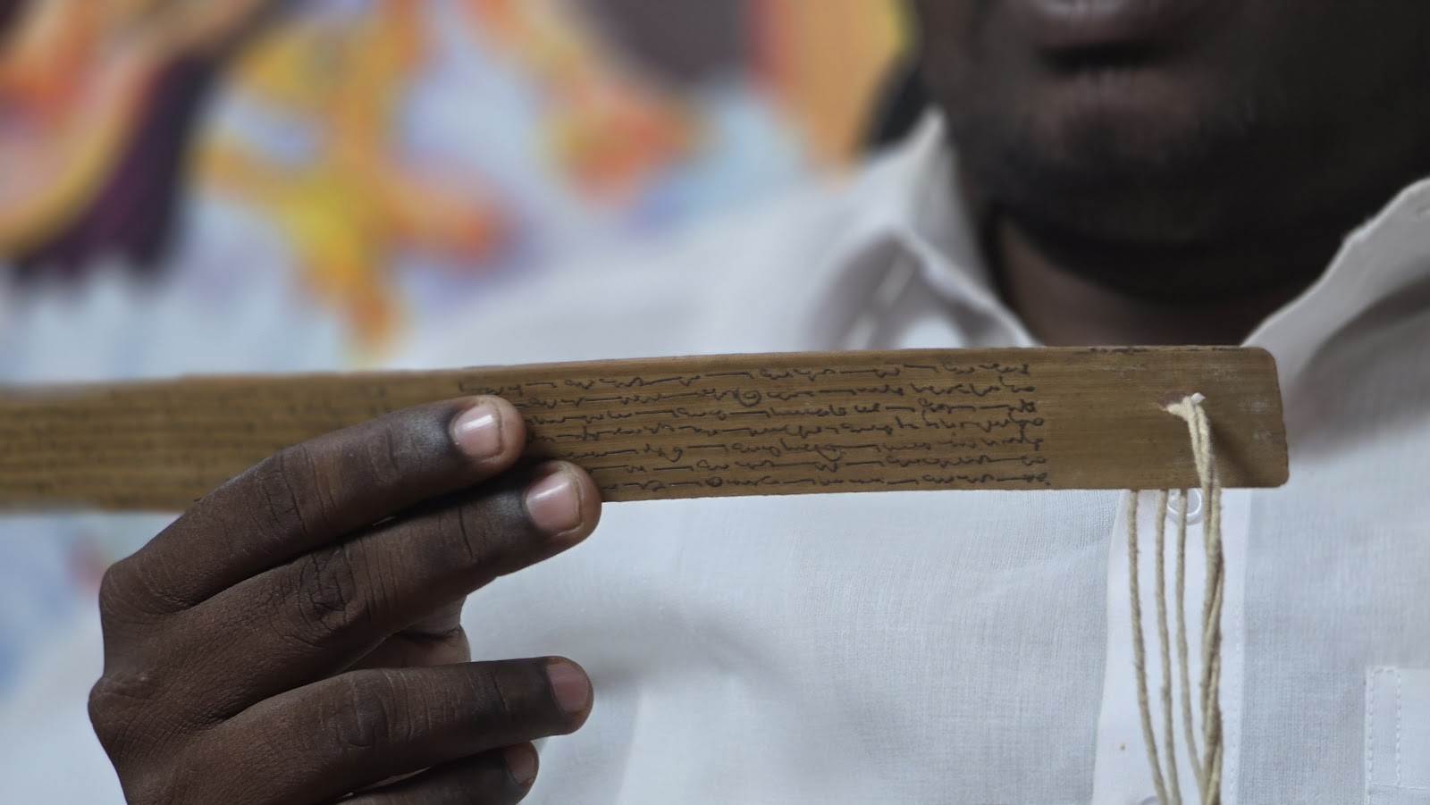 Close-up of a hand holding a single inscribed palm leaf