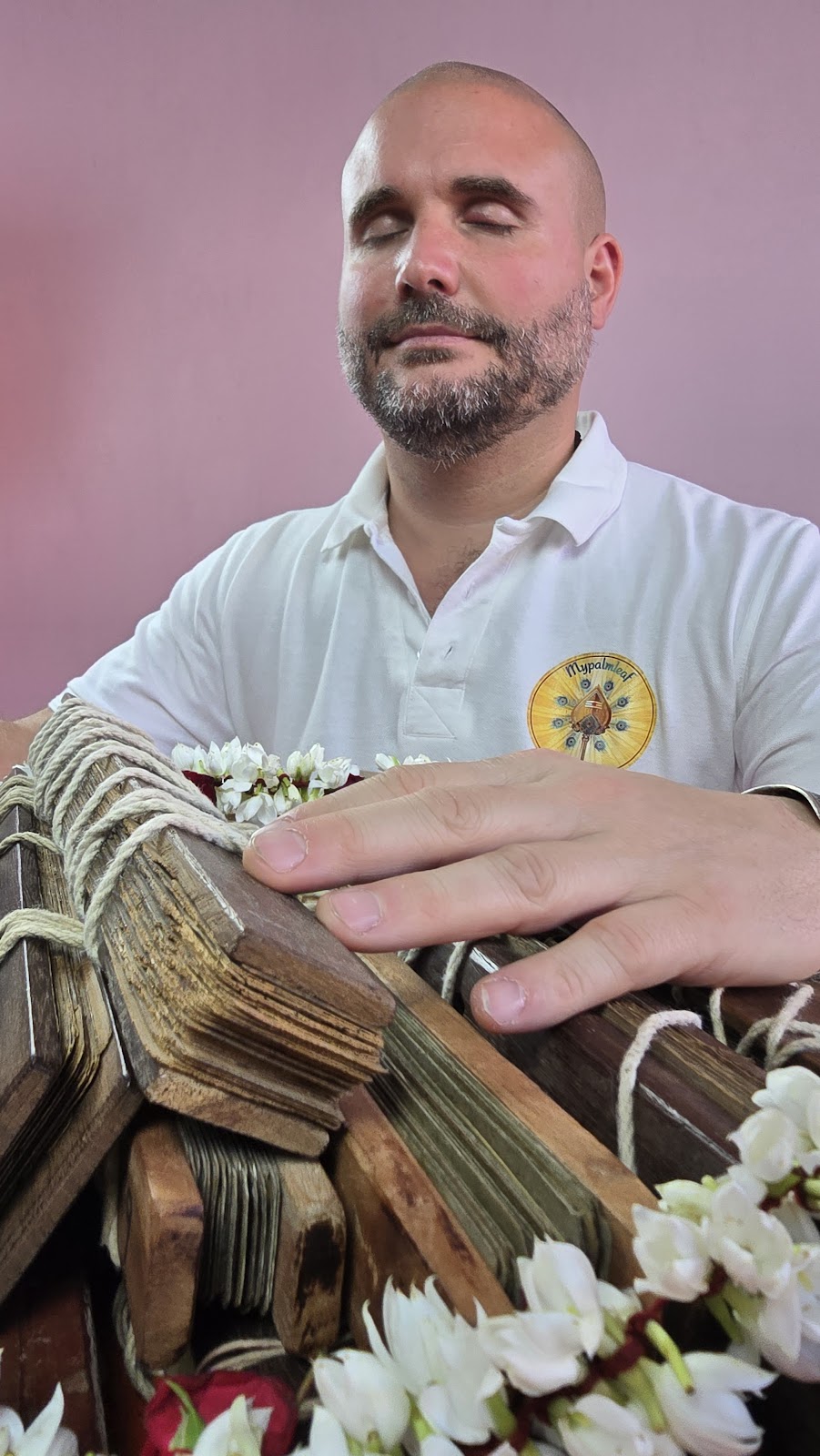 Mypalmleaf founder holding a garlanded palm leaf manuscript in meditation