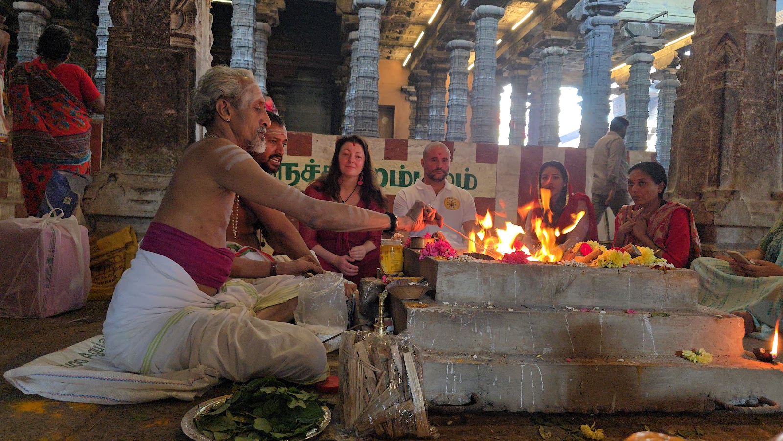Priest performing a homa fire ritual with devotees in a temple hall