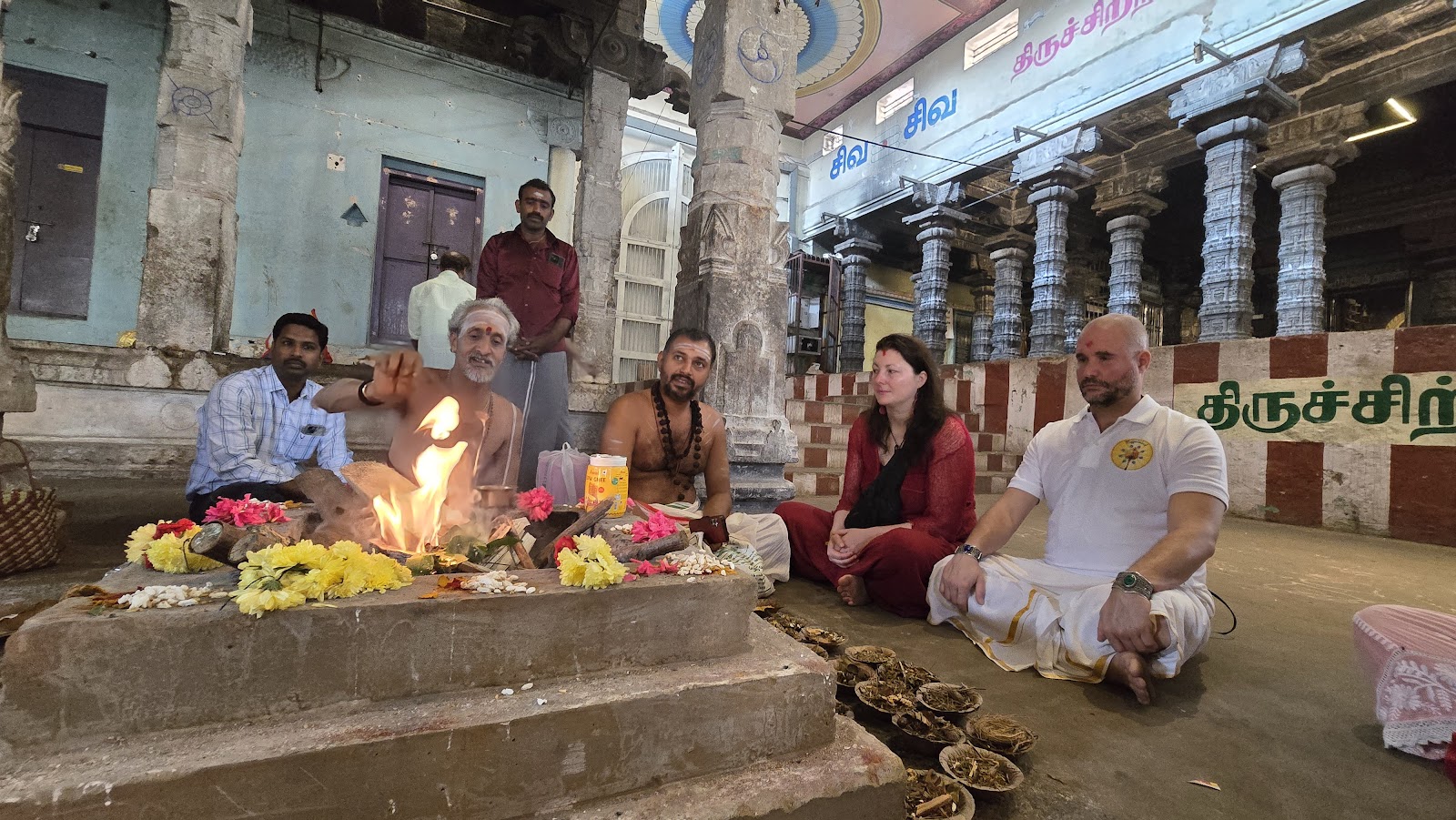 Mypalmleaf group seated around a homa fire with priests in a temple