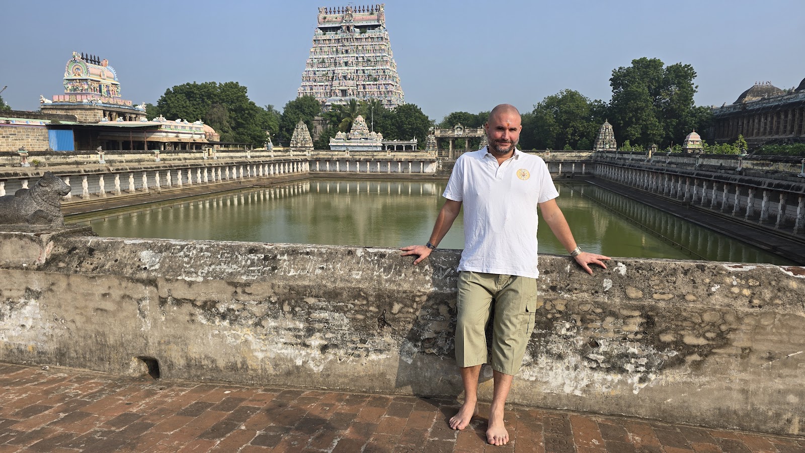 Mypalmleaf founder beside a temple tank with a gopuram behind