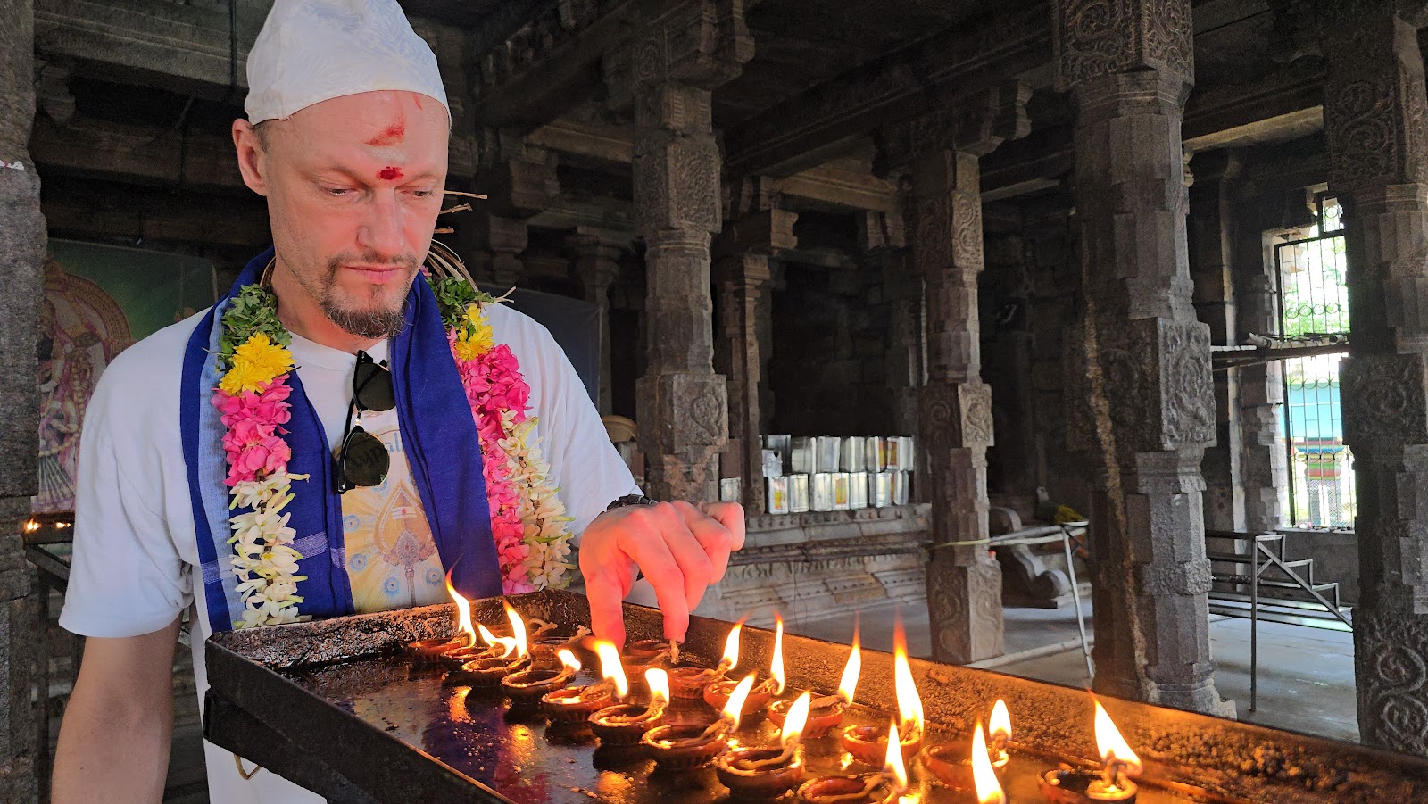 Visitor lighting rows of oil lamps at a South Indian temple